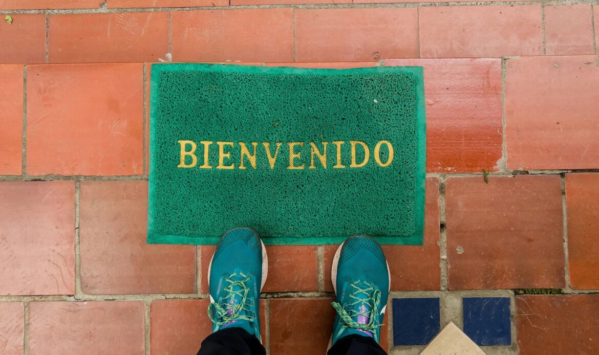 Somone standing in front of a welcome mat that reads 'Bienvenedo'