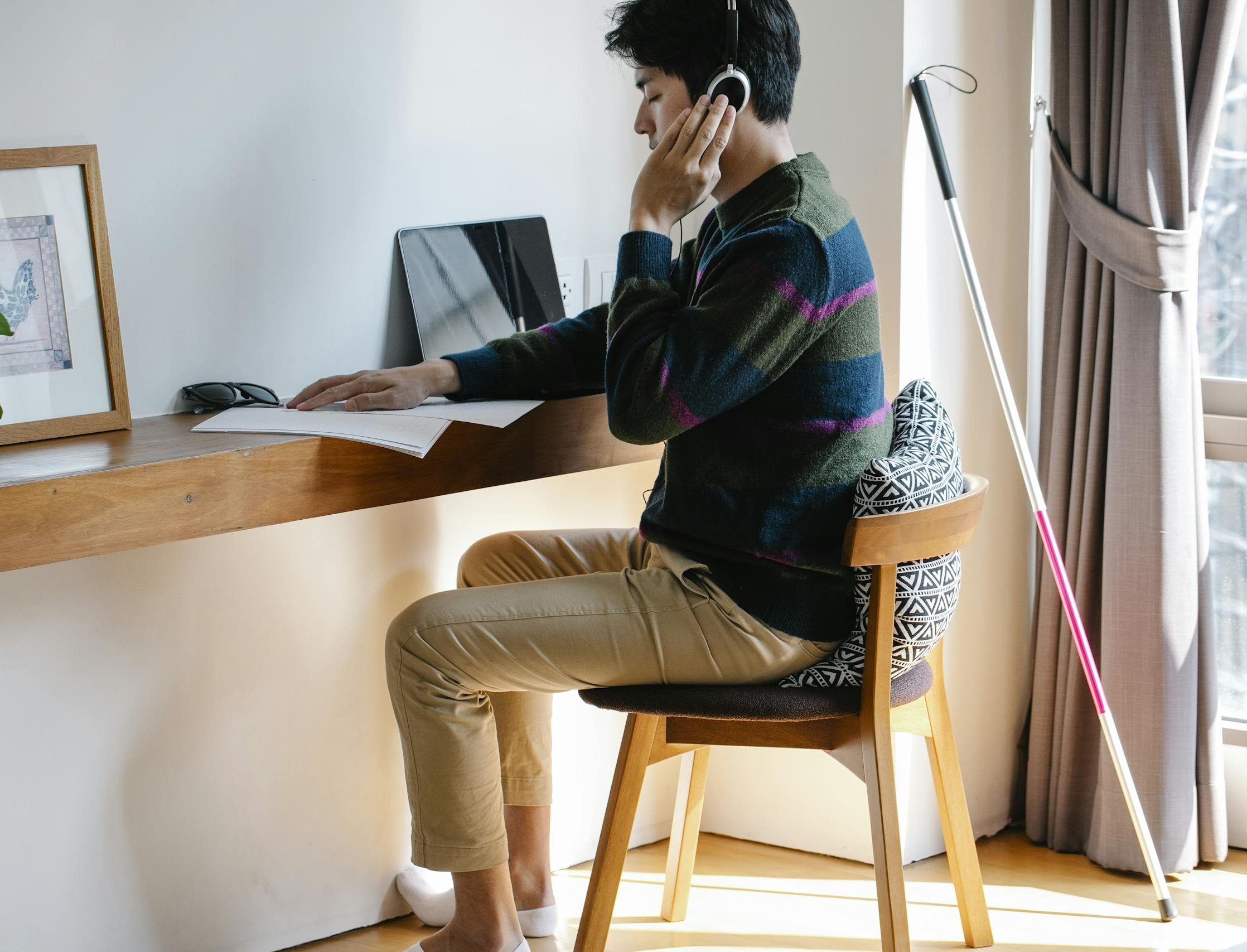 Man with visual impairment learning with headphones and braille indoors.